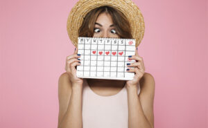 mulher segurando um calendário que marca os dias de seu período menstrual