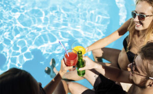 Amigos na piscina fazendo um brinde e aproveitando o verão.