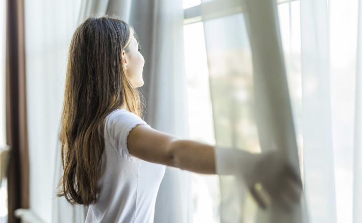 mulher abrindo as janelas, pois em um abiente arejado os agentes causadores de alergia se propagam menos
