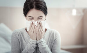 mulher assoando o nariz com crise alérgica