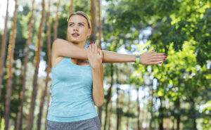 mulher se alongando para praticar atividades físicas, o que acelera o metabolismo