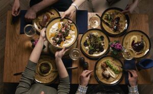 vista de cima de uma família à mesa com várias refeições diferentes em pratos bonitos