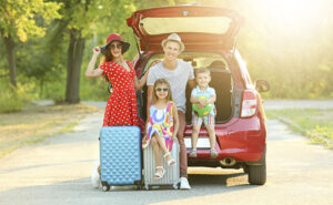 Família em um carro com o porta-malas aberto prontos para sair de viagem.