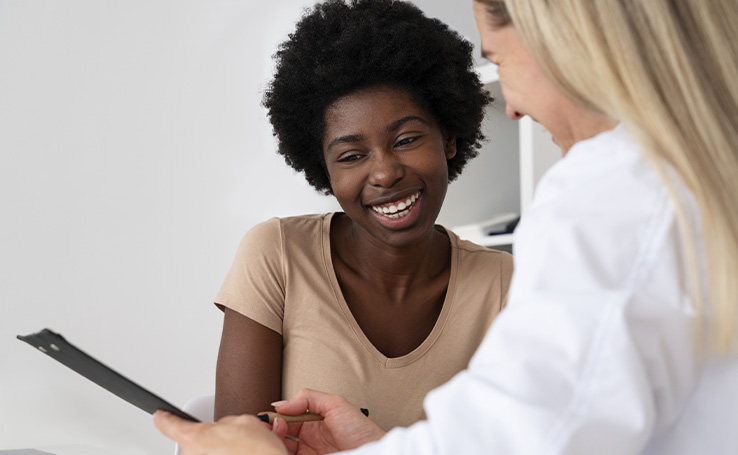 Mulher sorrindo em uma consulta médica para analisar seus exames de rotina