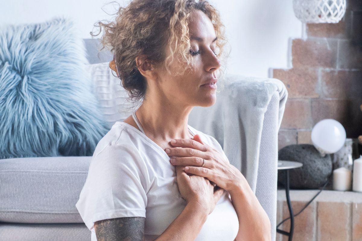 Mulher em casa meditando e se concentrando na respiração para melhorar sua saúde física e clareza mental alcançando serenidade